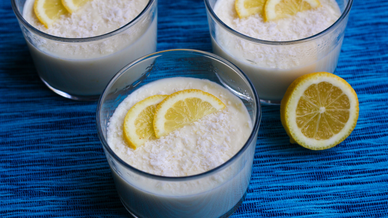 There are three jars of lemon pudding topped with lemon slices.