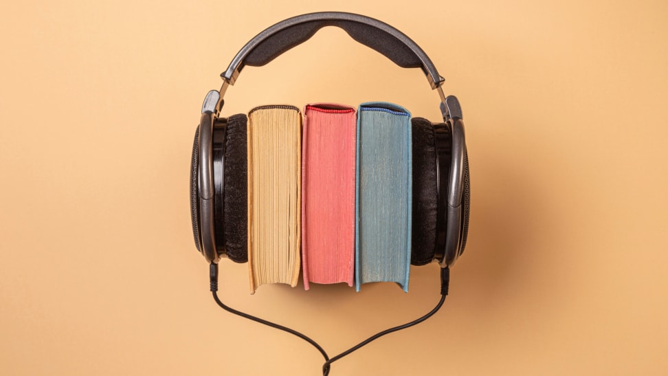 A stack of books with a pair of over-ear headphones around them on an orange background.