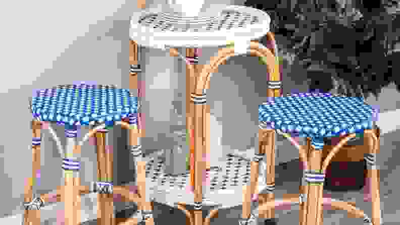 Two wicker stools with a wicker end table.