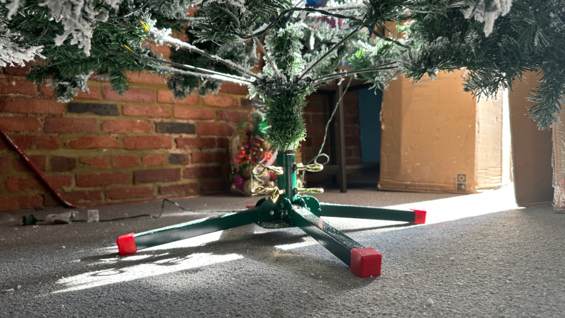A green and red powder-coated steel tree stand made for artificial Christmas trees.