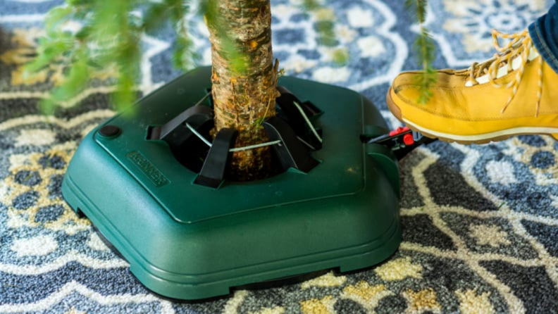 A person using the pedal on a tree stand to set it up.