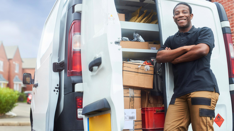 Repairman standing by van smiling