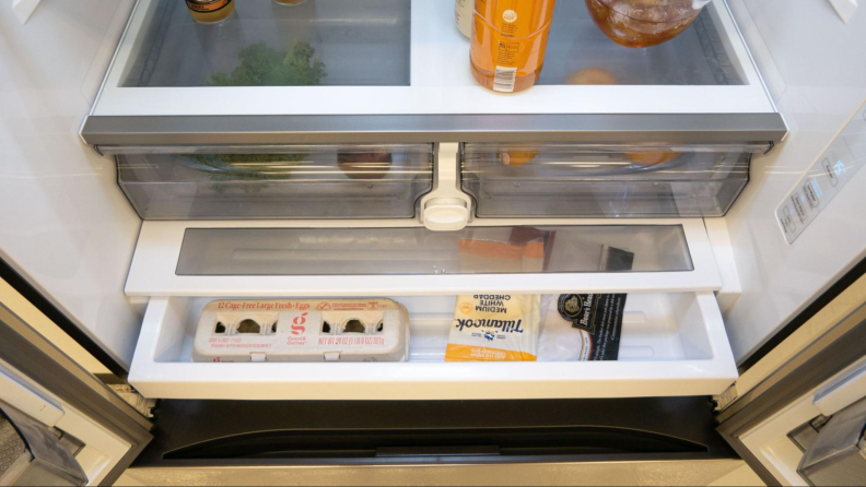 A close-up of the bottom half of the fridge compartment, showcasing items stored in the crispers and deli drawer.