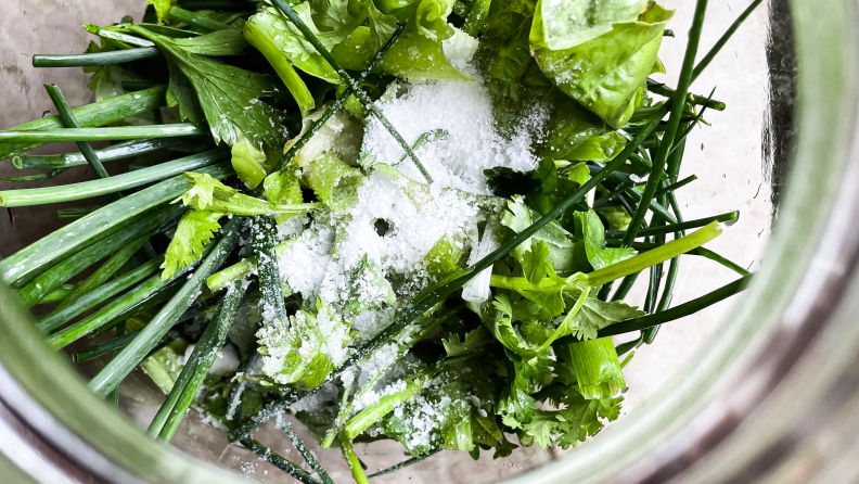 A closeup of green herbs and flaky salt.