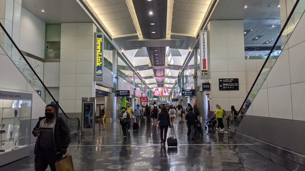 Masked people walk though an airport in 2021