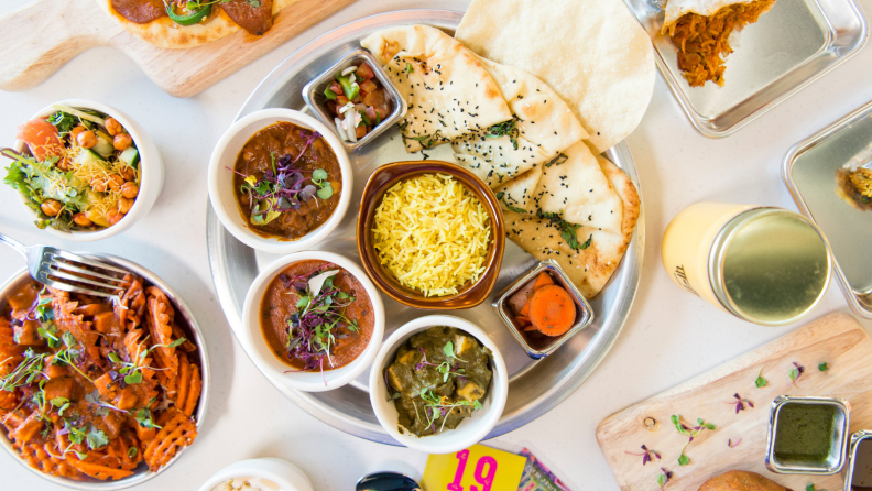 Multiple dishes from Curry Up Now Indian Street Food restaurant is on display.