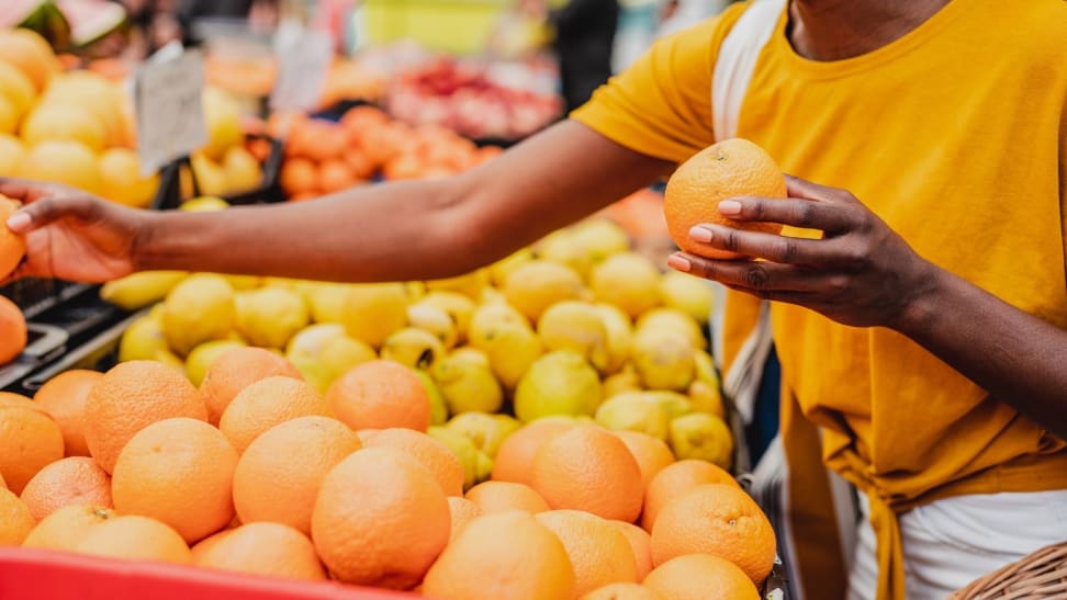 A person compares oranges at a grocery store.