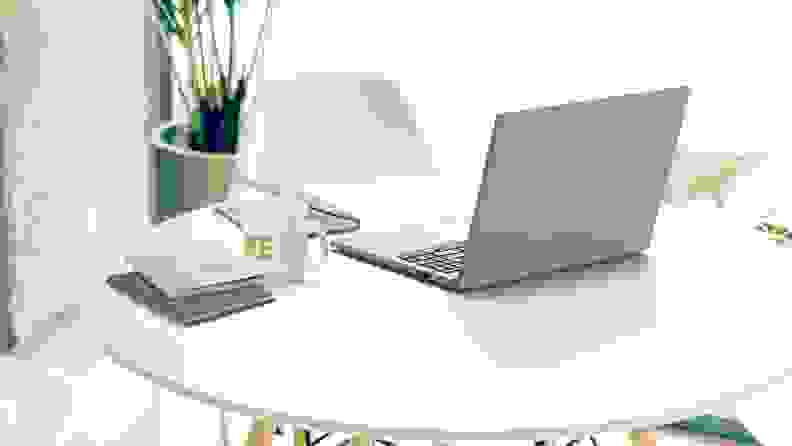 A light gray Acer Aspire Vero 16 sits on a white tabletop next to a coffee and notebooks.