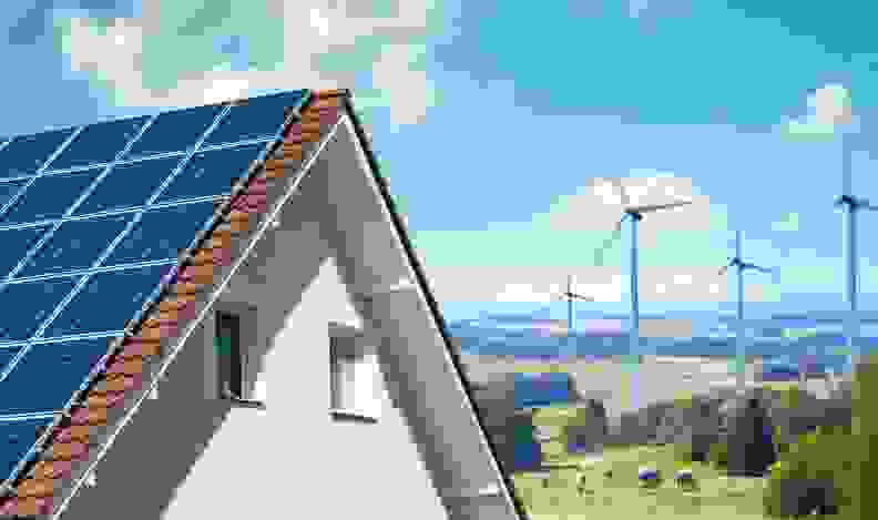 A home with wind turbines in the background.