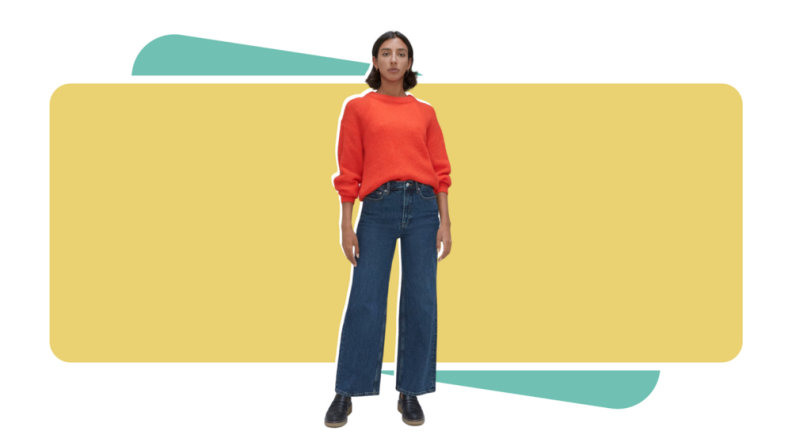 Woman wearing Everlane flare jeans and orange sweater.