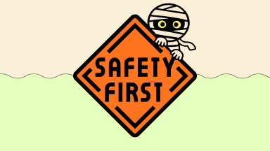 A mummy peeks over an orange sign that says Safety Firts