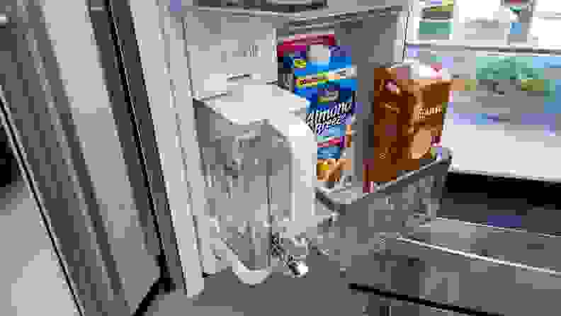 A close-up of the bottom interior of the fridge's left door, which houses a half-width storage bin next to the AutoFill water pitcher.