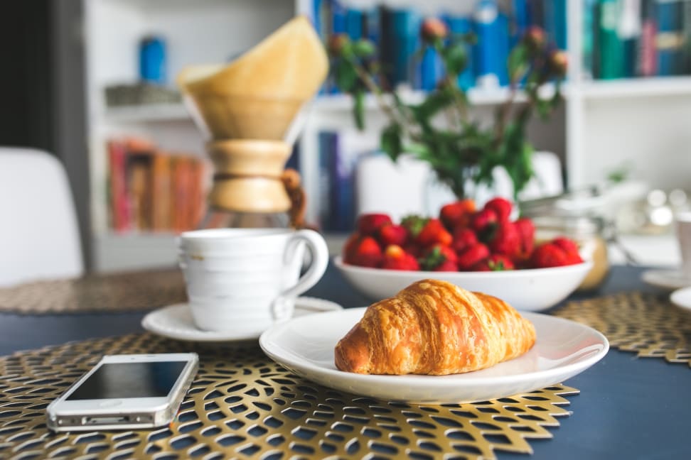 Coffee, strawberries, a croissant, and a smarpthone