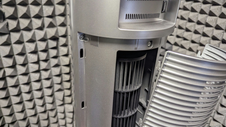 The air purifier stands in a soundproof room with its back grill removed.
