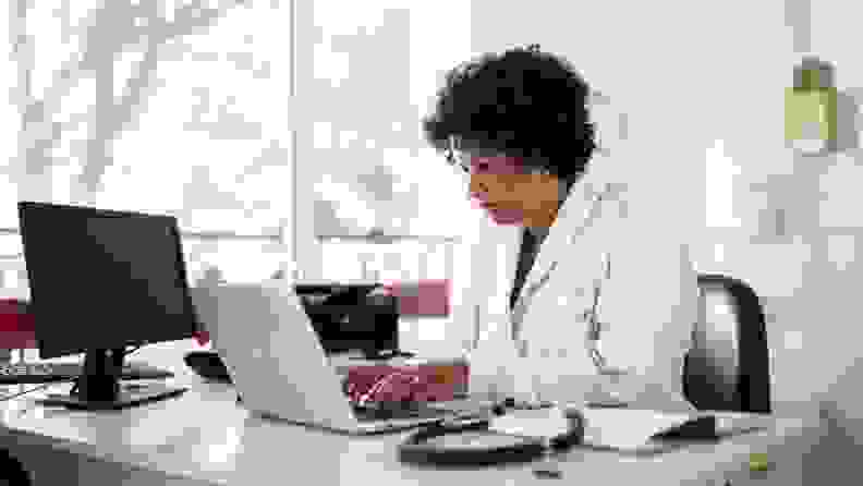 Female doctor in lab coat sitting at desk in office