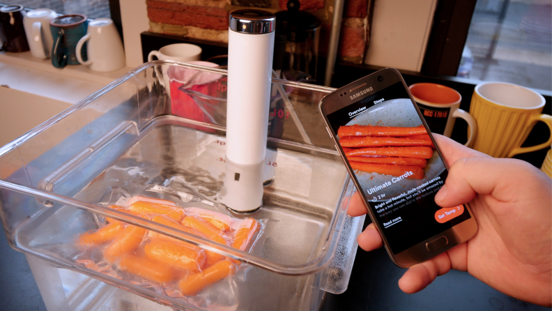 A Breville ChefSteps Joule immersion circulator cooks a bag of carrots in water.