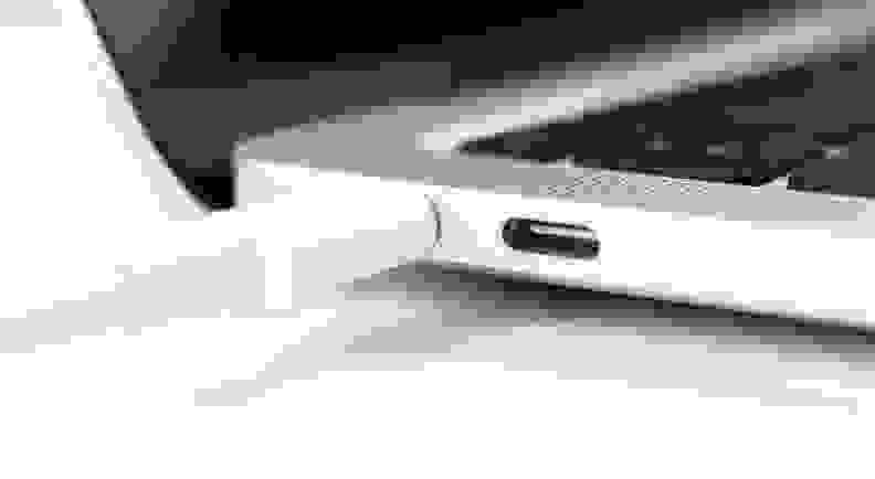 Charging battery laptop. Modern USB C port for fast charge. White cable plugged in laptop close-up view