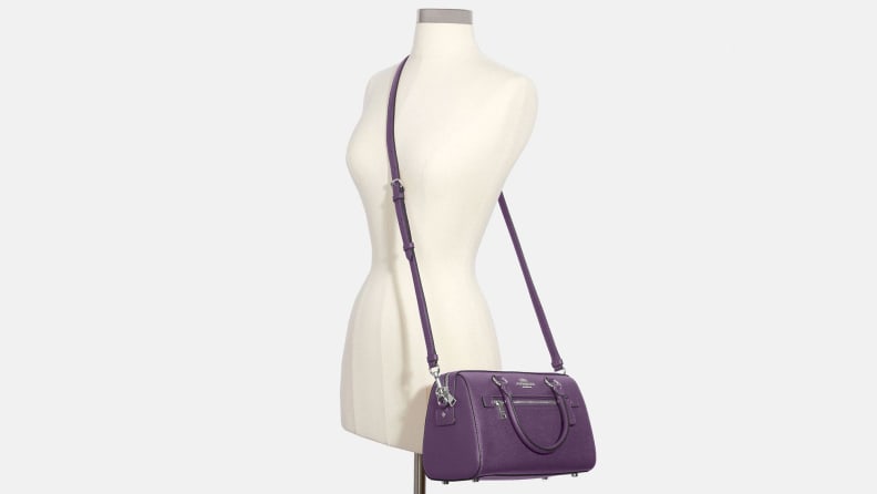A purple Coach cross body bag on a mannequin.