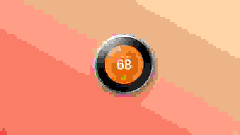 Google nest thermostat on orange background.