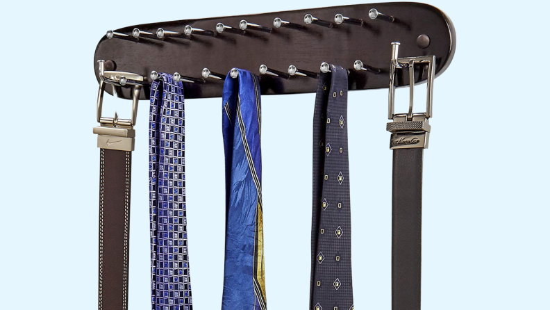 Tie rack with ties and belts on it.