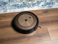 The iRobot j9+ on a wooden floor next to a carpet.