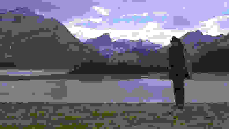 杰克（杰克·吉伦哈尔（Jake Gyllenhaal））独自站在河边，背景中有山。