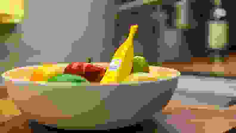 A banana phone sitting in a full fruit bowl
