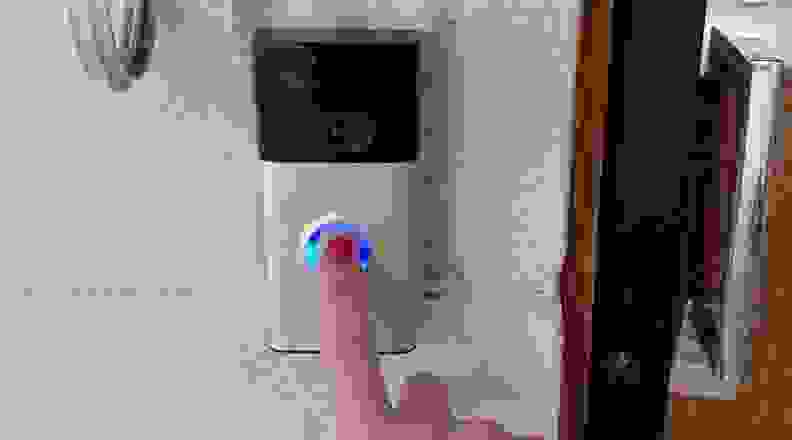 Finger with red nail polish pressing button of Ring Doorbell