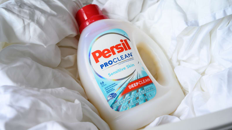 A bottle of Persil ProClean Sensitive laundry detergent on top of a white blanket