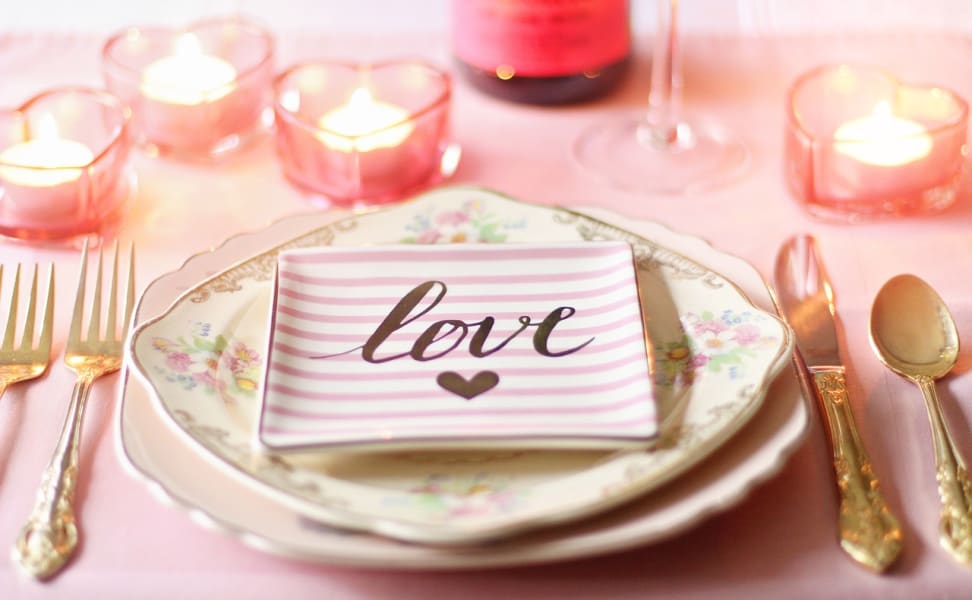 A table set with romantic decorations for a Valentine's Day dinner.
