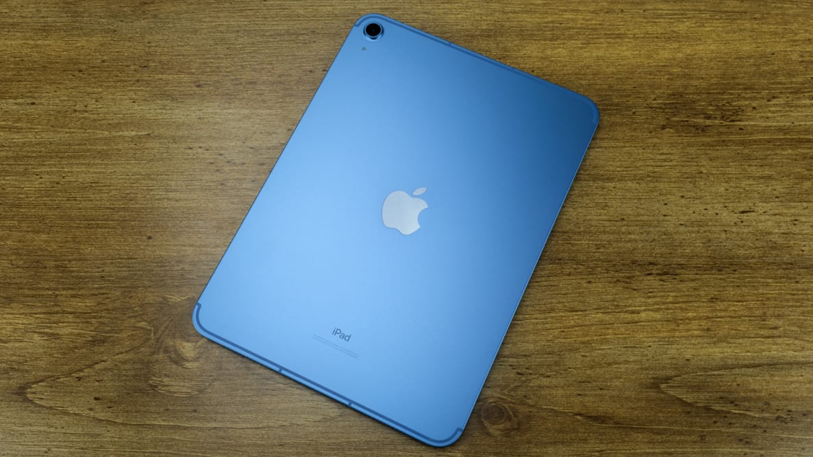 The grey-blue iPad (1oth generation) sits on a wooden desk with its back camera showing.