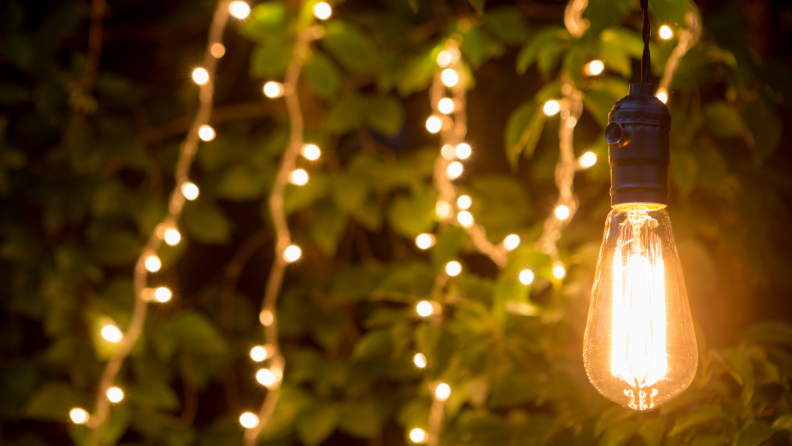 Close-up of an LED outdoor light bulb with string lights in the background