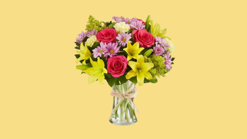 Vase of multi-colored flowers against yellow background