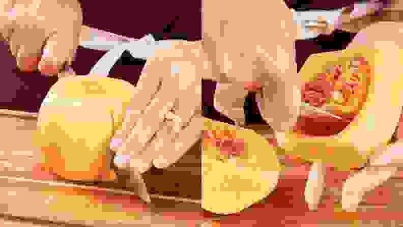 On left, person cuts the bulb section on raw butternut squash in half with knife and on right, uses a scooper to remove seeds.