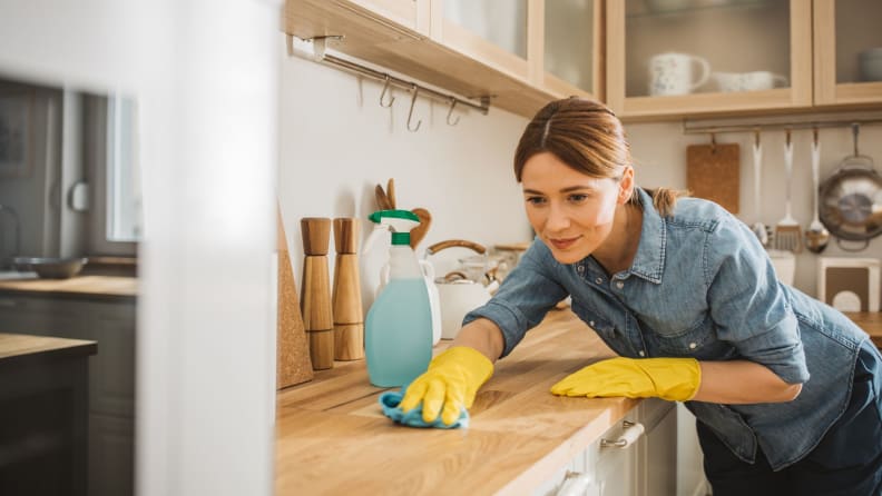 A woman wipes down a kitchen counter.