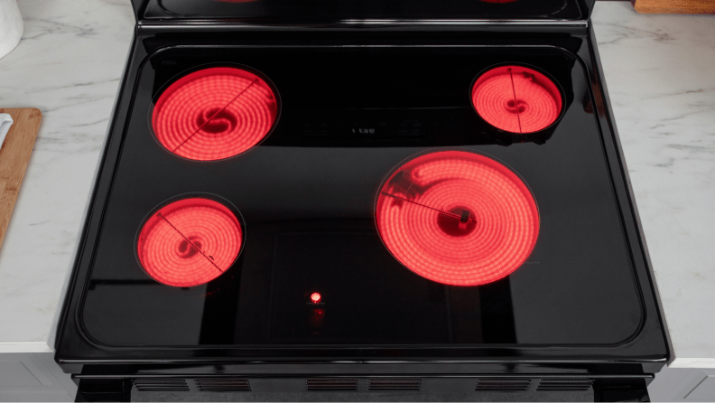 The stovetop of the electric range with all four burners turned on and glowing red.