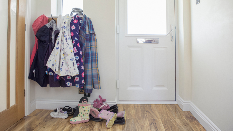 A messy entryway with coats and shoes.
