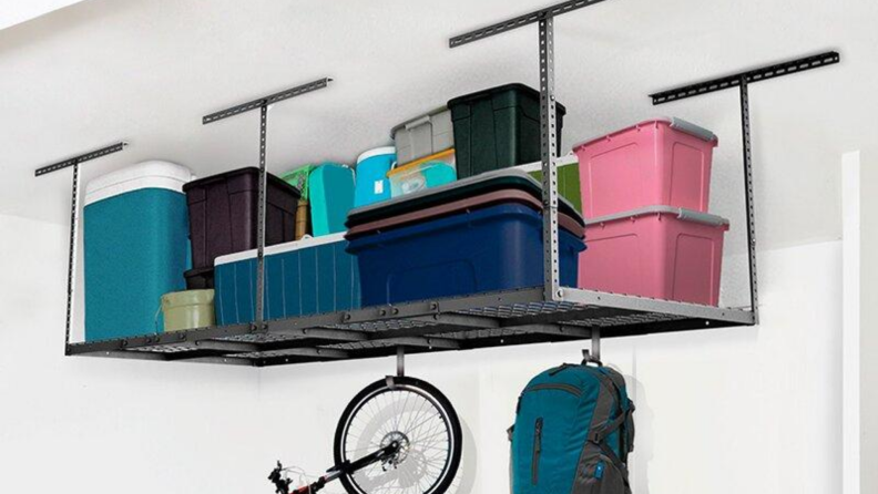 Overhead ceiling organizer in garage with coolers, bins, and other items, along with hanging hooks to hold a bike and backpack