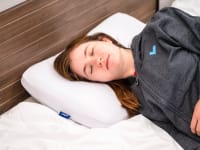 Person laying in bed with eyes closed on memory foam pillow.