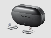 A black oval charging case sits on a gray surface with a pair of hearing aids