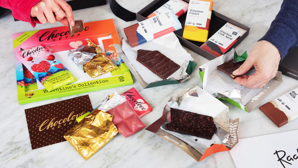 Two hands taking chocolate from a pile of various bars and wrappers