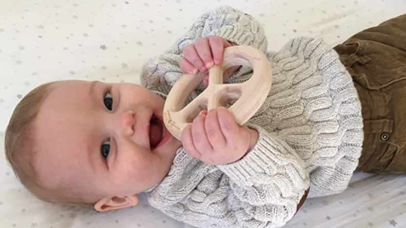 A baby smiles with their Maple Landmark toy