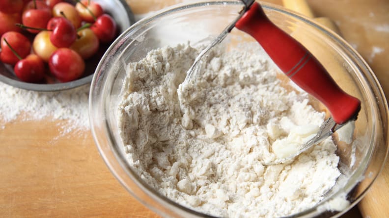 A pastry blender in a glass bowl of flour.