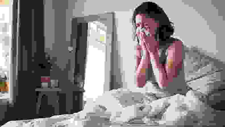 a woman sneezes in bed