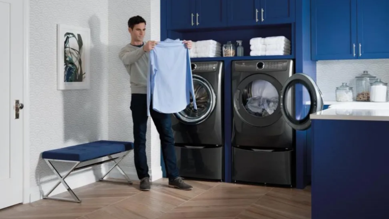 Man holding a shirt in front of a dryer