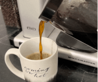 Moccamaster carafe pouring hot coffee into a mug