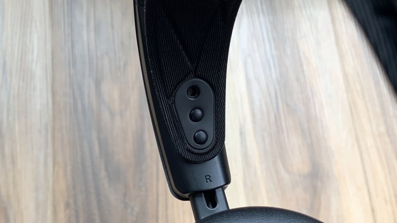 The Arctis Nova Pro's headband adjustment tabs are displayed against a wooden floor background.