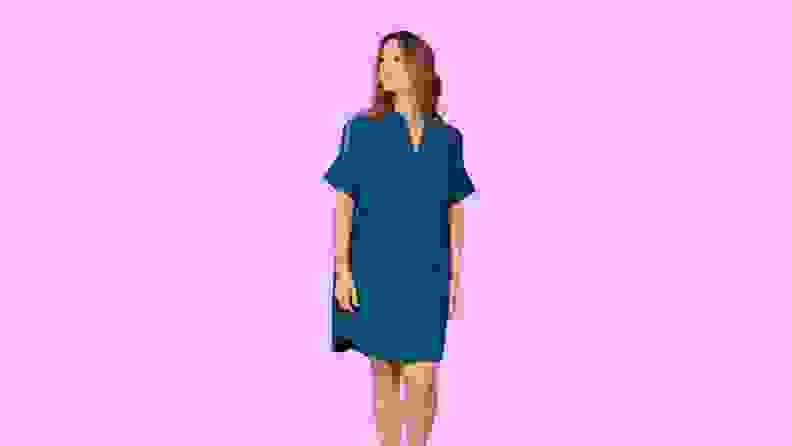 A woman modeling a dress in front of a background.