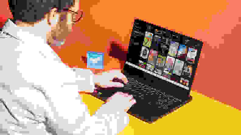 A person typing on the Lenovo IdeaPad Gaming 3 with an orange background.