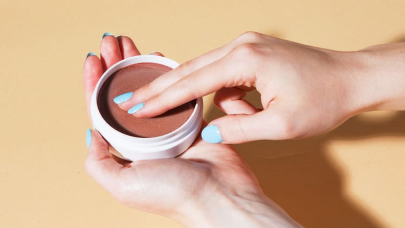 Person using two fingers to test out bronzer.